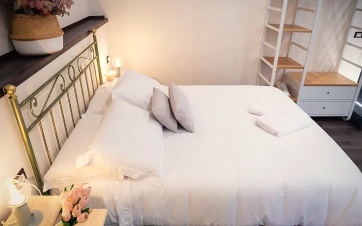 Il letto matrimoniale con la testiera d'ottone, i cuscini e gli asciugamani piegati