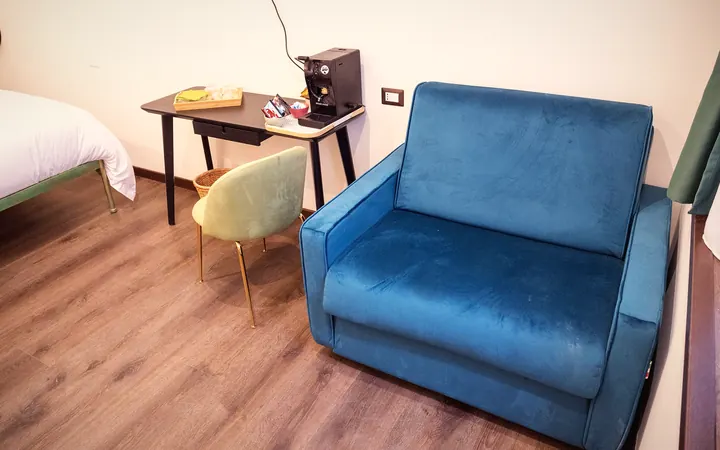 La poltrona di velluto blu accanto allo scrittoio con la macchinetta del caffè